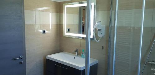 a bathroom with a sink and a shower with a mirror at Yellow Cube Holiday Apartments in Kožino