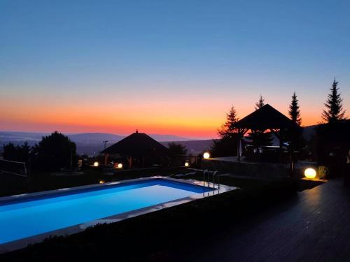 a swimming pool with a sunset in the background at Apartamenty Pod Łysicą & SPA - przy stoku, basen, jacuzzi, sauna in Krajno Pierwsze