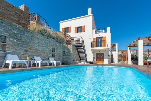 a villa with a swimming pool in front of a building at Belvedere Andros in Batsi