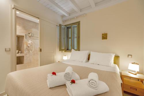a bedroom with a large white bed with towels at Belvedere Andros in Batsi