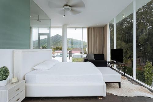 a white bedroom with a white bed and a tv at Beach House Zambales in San Antonio