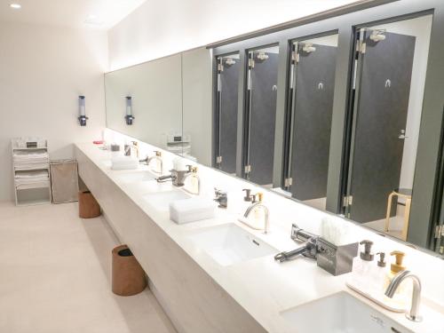 a bathroom with a row of sinks and mirrors at LEO YU Capsule Hotel Nishifunabashi in Funabashi