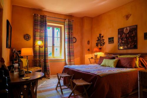 a bedroom with a bed and a table and a window at Maison d'Hôtes Mas de Barbut in Saint-Laurent-dʼAigouze