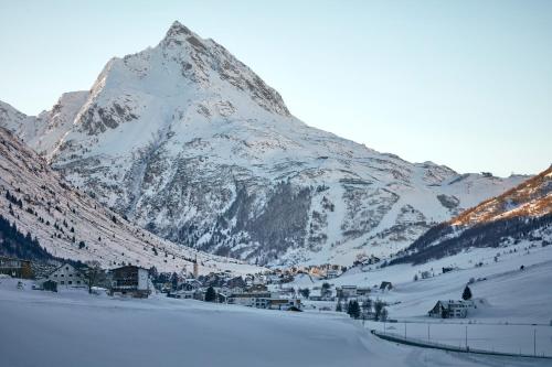 a snow covered mountain with a village in front of it at Hotel Zontaja Superior in Galtür
