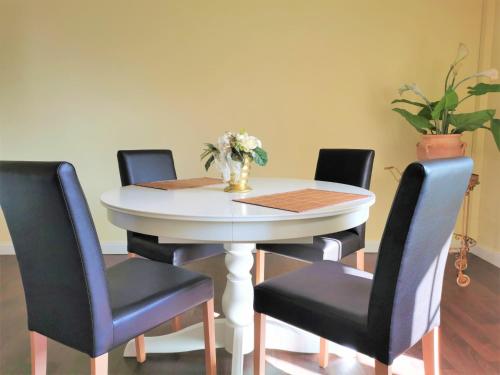 a white table with four chairs and a vase with flowers at Spilburg Apartments in Wetzlar