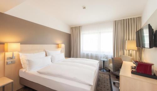 una camera d'albergo con un grande letto bianco e una TV di Hotel Lyskirchen a Colonia