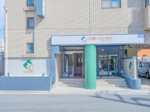 a building with a green column in front of it at LEO YU Capsule Hotel Nishifunabashi in Funabashi