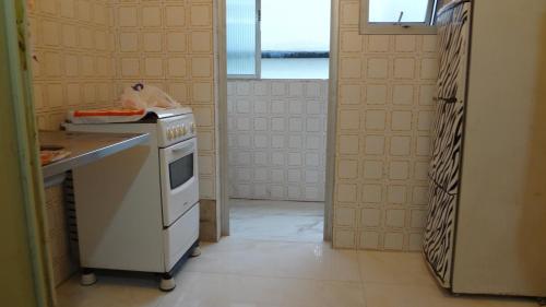 eine Küche mit einem Herd, einem Waschbecken und einem Fenster in der Unterkunft Apartamento Guaruja Bacaitava in Guarujá