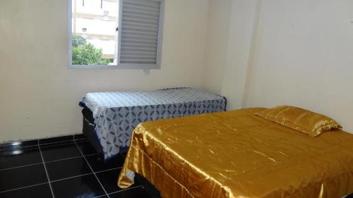 a room with two beds and a window at Apartamento Guaruja Bacaitava in Guarujá