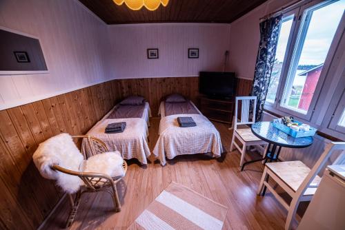 a room with two beds and a table and a television at Arctic Guesthouse & Igloos in Ranua