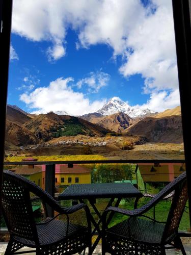 a table and chairs on a balcony with a mountain view at North Kazbegi in Stepantsminda
