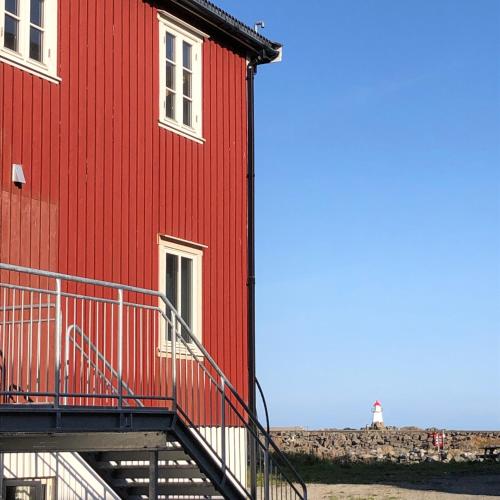 a red building with a staircase next to a lighthouse at Laukvik Suites in Laukvik