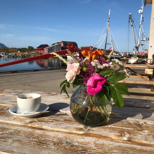 a vase filled with flowers next to a cup of coffee at Laukvik Suites in Laukvik