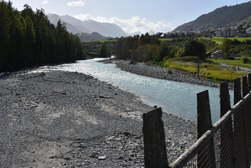 a river with a fence in front of a river at Guardamunt in Scuol