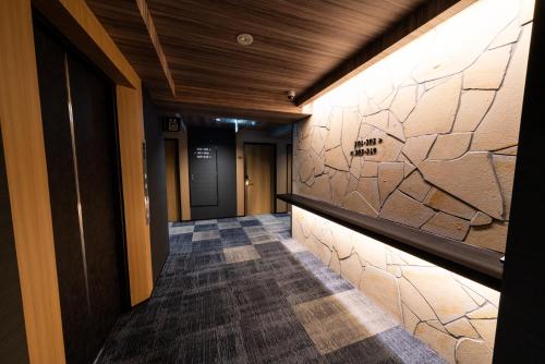 a hallway of a building with a stone wall at The Celecton Kurume in Kurume