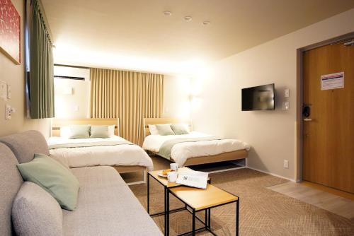 a hotel room with two beds and a couch at Koti Sopo Universal Bay 1 by Liaison in Osaka