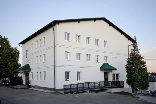 a large white building with a tree in a parking lot at F Hotel in Hörsching