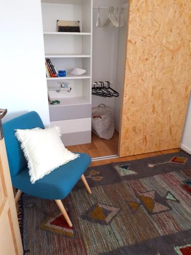 Cette chambre comprend une chaise bleue et un placard. dans l'établissement Maison Eli (charming basque house in Guéthary village), à Guéthary