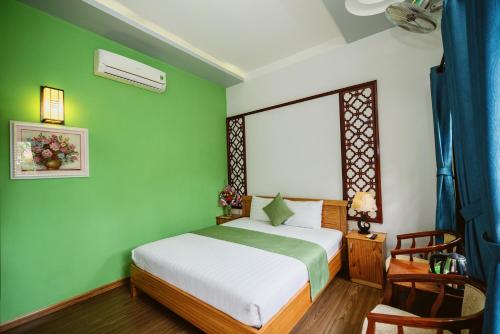 a bedroom with a bed and a green wall at Tue Tam Garden Villa in Hoi An