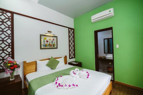 a bedroom with a white bed with a green wall at Tue Tam Garden Villa in Hoi An