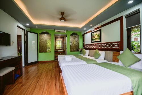 two beds in a room with green walls at Tue Tam Garden Villa in Hoi An
