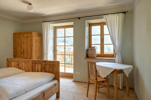 a bedroom with a bed and a desk and windows at Villa Messner in Funes