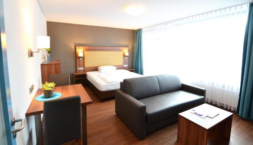 ハイデルベルクにあるNeu Heidelberg - Guesthouse & Apartmentsのベッド、ソファ、テーブルが備わるホテルルームです。