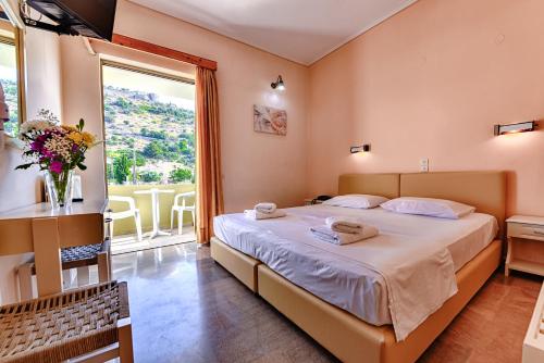 a bedroom with a large bed and a large window at Ionis Hotel in Karavádhos