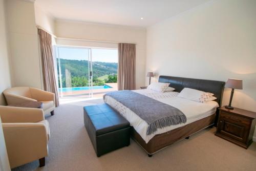 a bedroom with a bed and a chair and a window at Brackenridge 11 Protea Dale in Plettenberg Bay