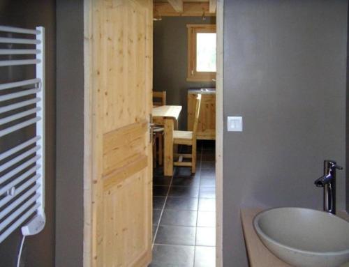 ein Bad mit einem Waschbecken und einer Tür zur Küche in der Unterkunft Le Chalet des Neiges in Thiéfosse
