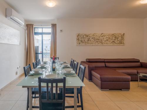 a dining room with a table and a couch at Seashells 2 Bedroom Apartments with terrace, just off the Bugibba promenade - by Getwaysmalta in St. Paul's Bay