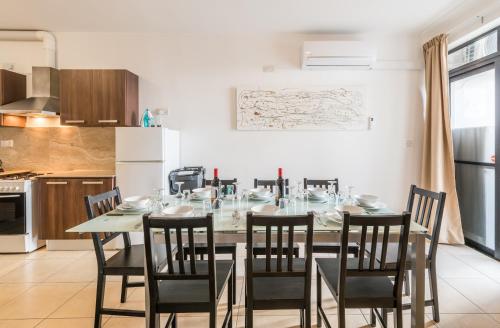 a dining room with a table and chairs in a kitchen at Seashells 2 Bedroom Apartments with terrace, just off the Bugibba promenade - by Getwaysmalta in St. Paul's Bay