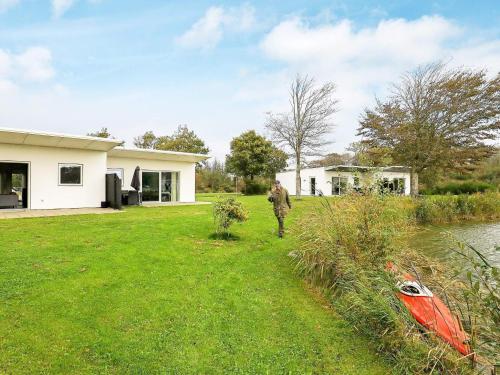 Un uomo che cammina in un giardino vicino a una casa di 6 person holiday home in Ringk bing a Ringkøbing