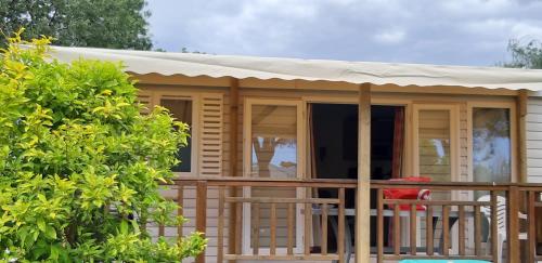 a large wooden cabin with a porch with a roof at Mobil Home dans camping Lattes in Lattes
