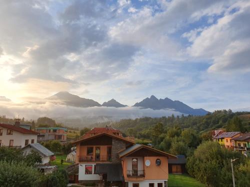 een dorp met bergen op de achtergrond met een bewolkte hemel bij Vila Somani in Nová Lesná