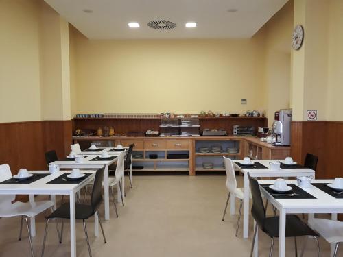 a restaurant with white tables and chairs and a kitchen at Hotel Palacio de Garaña in Garaña