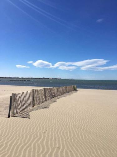 a wooden fence on a sandy beach near the ocean at Mobil Home dans camping Lattes in Lattes