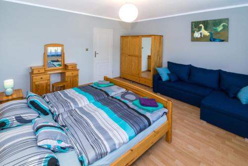 een slaapkamer met een groot bed en een blauwe bank bij Pokoje gościnne Norbu in Kudowa-Zdrój