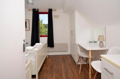 Zimmer mit einem Schreibtisch, einem Tisch und einem Fenster in der Unterkunft Cottage 346 - Clifden in Clifden