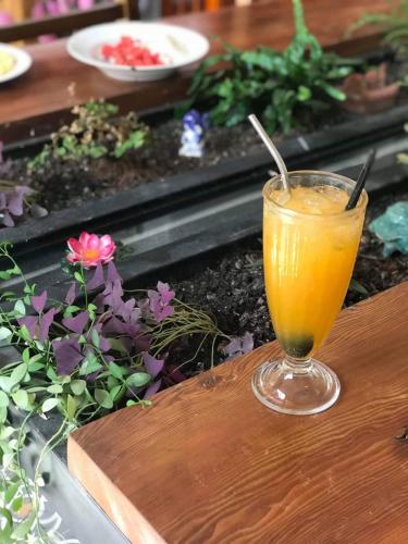 a glass of orange juice sitting on a wooden table at Pink Tulip Hoi An in Hoi An