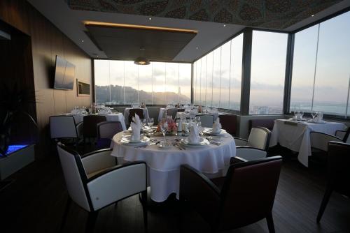 a restaurant with white tables and chairs and large windows at AZ Hôtels Kouba in Alger