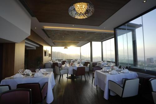a restaurant with white tables and chairs and windows at AZ Hôtels Kouba in Alger