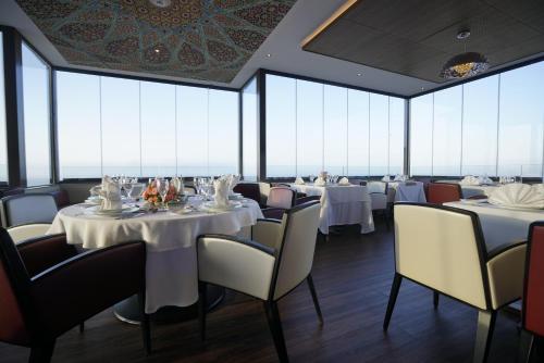 a restaurant with white tables and chairs and large windows at AZ Hôtels Kouba in Alger