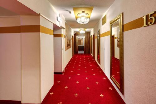 a hallway with a red carpet and a long corridor at TIPTOP Hotel Burgschmiet Garni in Nürnberg
