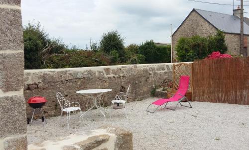 eine Terrasse mit rosa Stühlen, einem Tisch und einem Zaun in der Unterkunft La Boulangerie, charmant cocon pour déconnecter in Montfarville