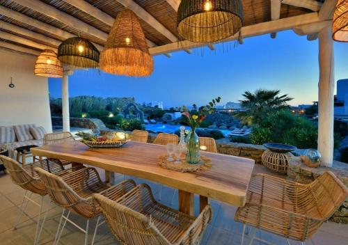 a dining room with a wooden table and chairs at Leno Villas Mykonos in Mýkonos City