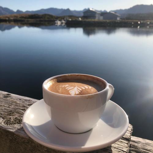 a cup of coffee sitting on a table near the water at Laukvik Suites in Laukvik
