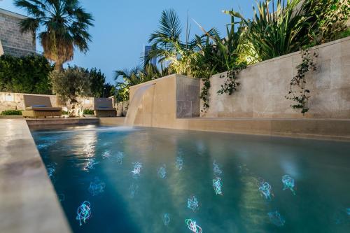 a swimming pool with blue water and palm trees at Boutique Hotel & Spa Casa del Mare - Mediterraneo in Herceg-Novi