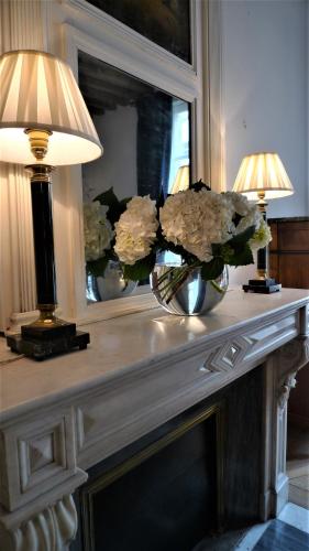 une table avec un vase et des fleurs sur lui dans l'établissement Les chambres de l'Abbaye, à Caen