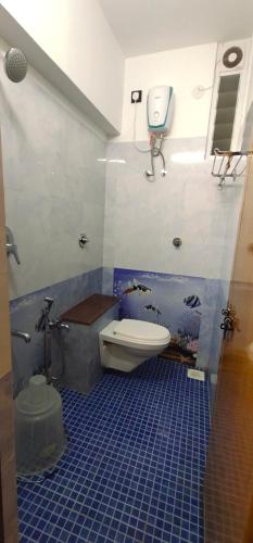a blue tiled bathroom with a toilet and a sink at Krishna Kausthubha in Udupi